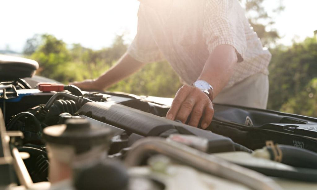 Asian senior examining his broken-down car on the roadside – key things to inspect before a long car journey